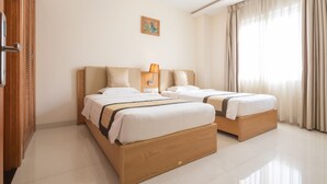 Habitación de hotel con dos camas, un armario de madera, un cuadro en la pared y una ventana con cortinas.