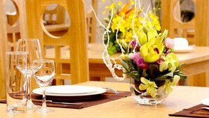 Una mesa de comedor dispuesta con varias copas de vino, platos y un centro de mesa con flores amarillas.