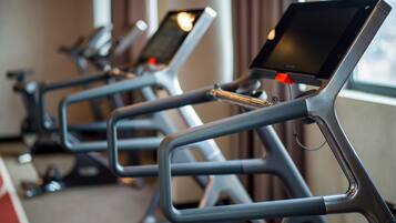 Une rangée de vélos d’appartement équipés d’écrans numériques, probablement dans une salle de sport ou un centre de remise en forme.