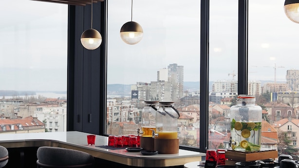 Un espace bar avec vue sur la ville, une grande tireuse à bière et un grand bocal rempli de citrons et de menthe.