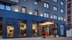 Un hôtel moderne à la façade sombre, doté de grandes fenêtres et d’une entrée bien éclairée.