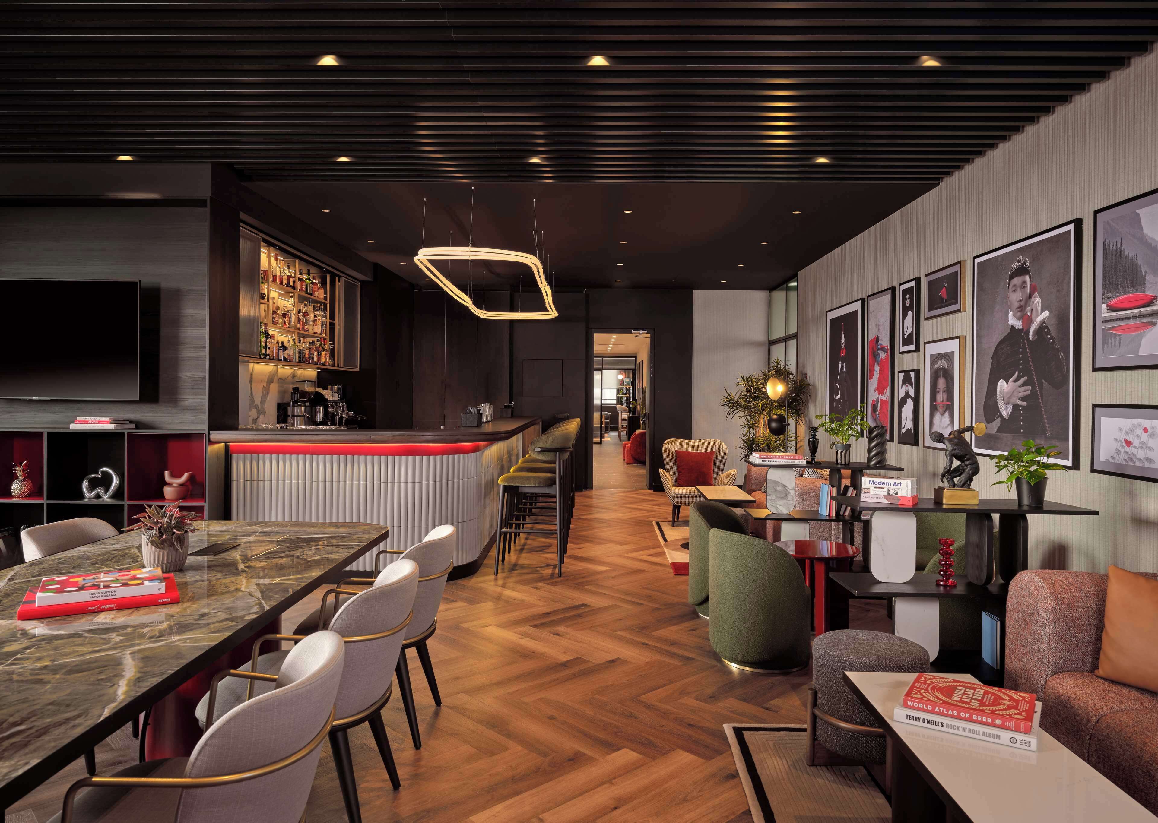 A modern bar area with a counter, seating, and a TV screen.