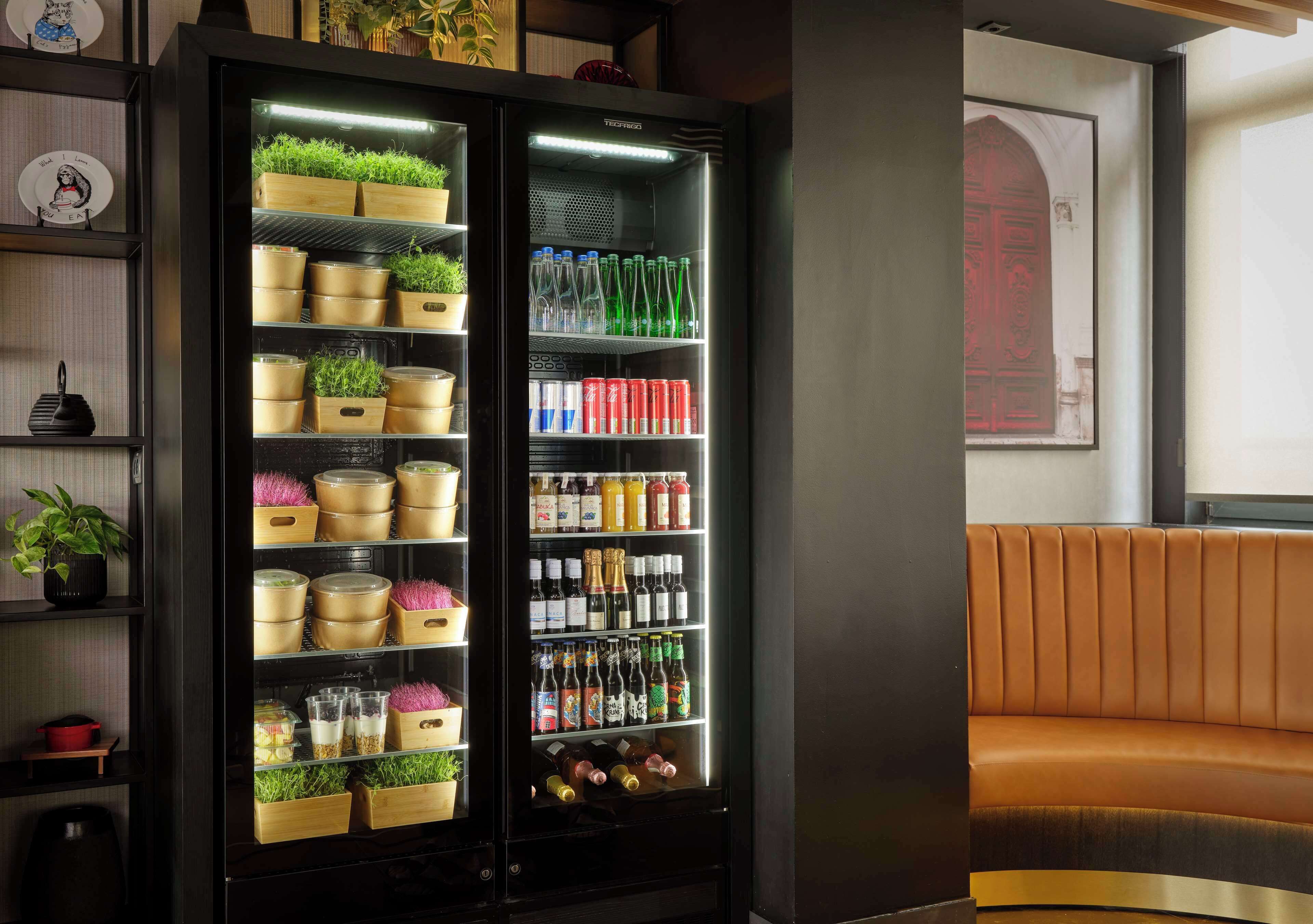 A modern hotel room with a black minibar, wooden storage units, and a brown leather sofa.