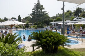 A pool area with lounge chairs and umbrellas, surrounded by greenery and trees. - Hotel Santa Lucia (Santa Cesarea Terme)
