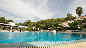 A swimming pool with lounge chairs and umbrellas, surrounded by trees and a building in the background. - Hotel Santa Lucia (Santa Cesarea Terme)