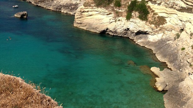 A coastal area with clear turquoise water, rocky cliffs, and a sandy beach. - Hotel Santa Lucia (Santa Cesarea Terme)