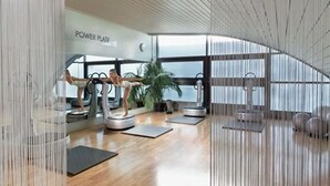 A modern gym with exercise equipment, large windows, and a wooden floor. - Aspria Berlin Ku’damm – Sport & Spa (Berlin)