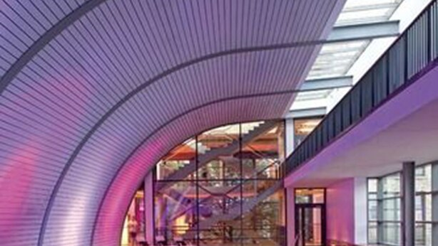 A modern indoor swimming pool with a curved ceiling and glass walls, allowing natural light to enter. - Aspria Berlin Ku’damm – Sport & Spa (Berlin)