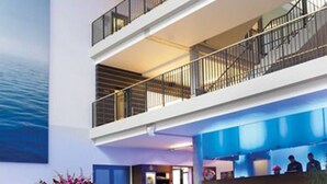 A multi-level hotel lobby with a staircase, a reception desk, and a large painting on the wall. - Aspria Berlin Ku’damm – Sport & Spa (Berlin)