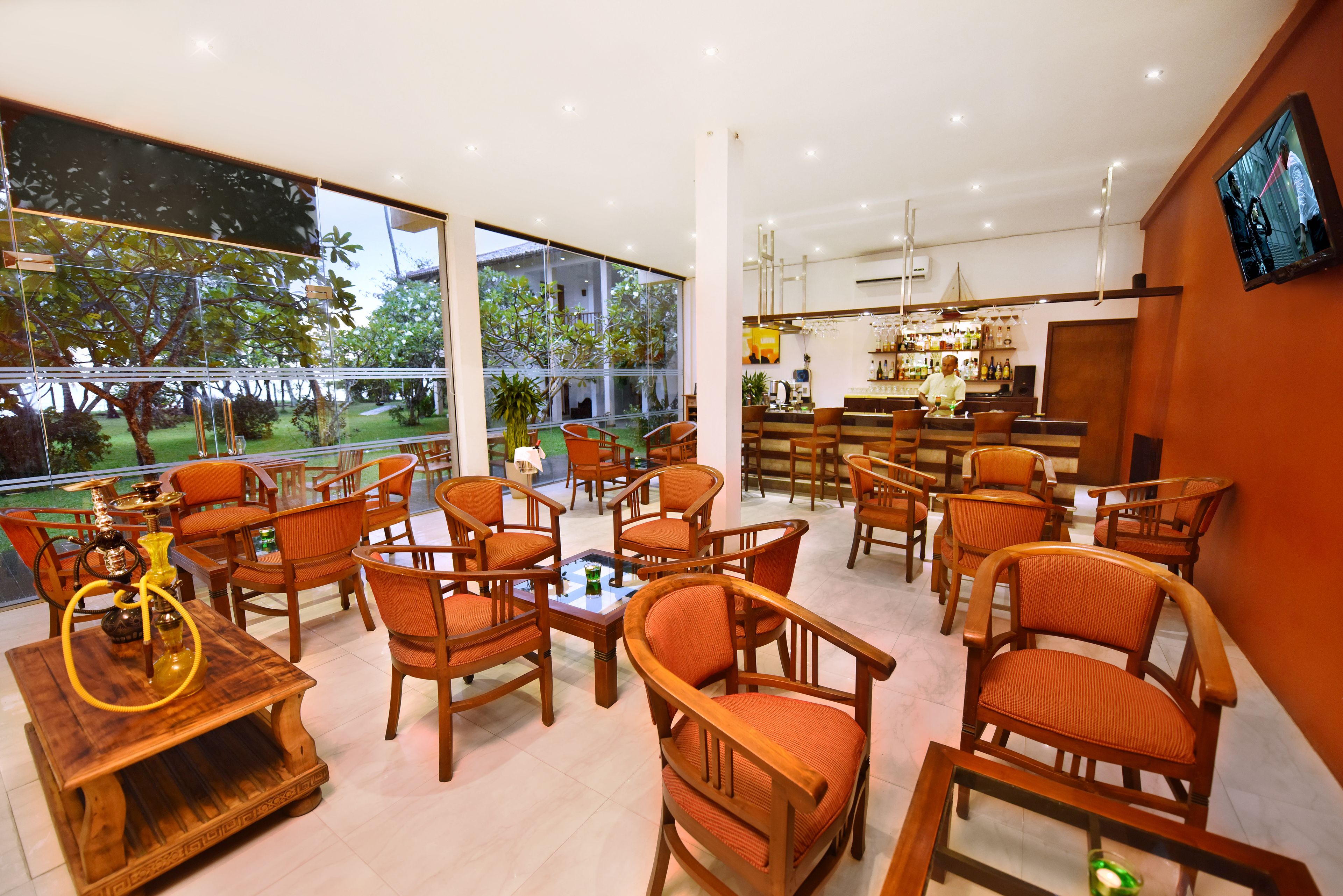 A modern bar area with wooden furniture and large windows offering a view of the outdoors.