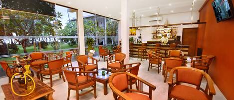 A modern bar area with wooden furniture and large windows offering a view of the outdoors.