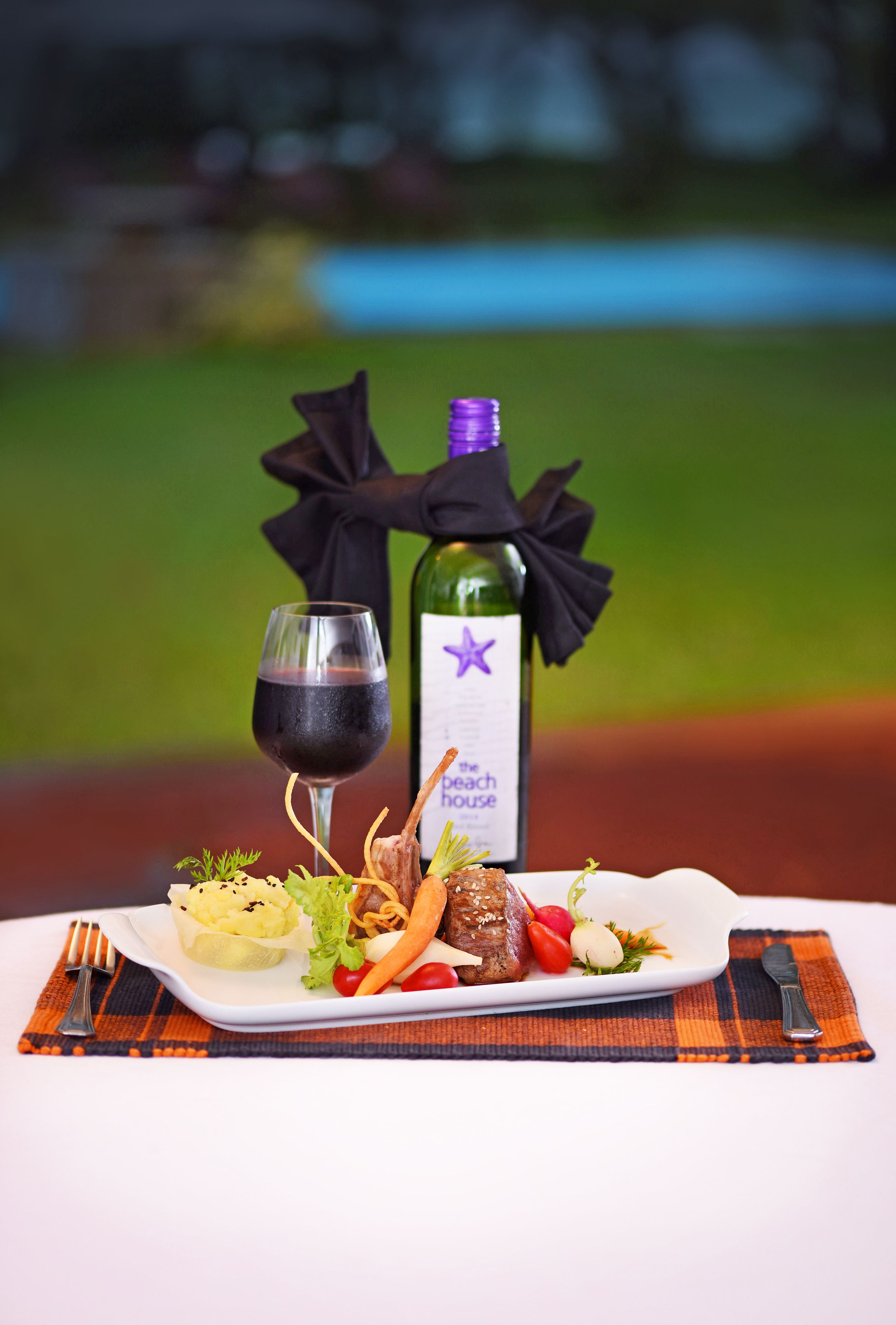 A plate of food with a bottle of wine and a glass of wine on a table.