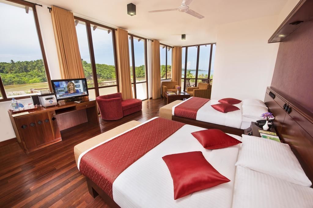 A hotel room with two beds, a desk, and a TV.