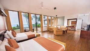 A hotel room with two beds, a sitting area, and a balcony with a view of the ocean. - Mandara Resort (Weligama)
