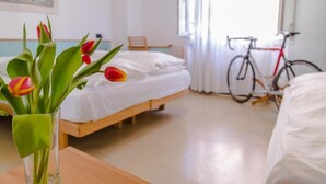 A hotel room with a bed, a bicycle, and a vase of tulips on a table. - Hotel Martinelli (Ronzo-Chienis)