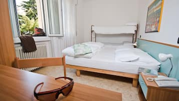 Een kamer met een stapelbed, een bureau met stoel, een paar brillen, een lamp en een radiator.