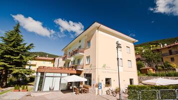 Un hotel de varios pisos con restaurante, bar, terraza al aire libre y montañas de fondo.