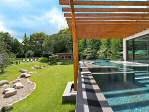 Un espace piscine extérieur moderne, agrémenté d’une pergola en bois, d’une pelouse bien entretenue et d’un chemin de pierre menant à la piscine.