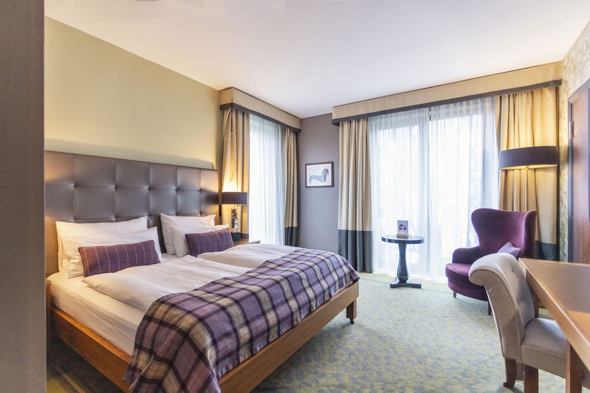 Una habitación de hotel con una cama grande, un escritorio, una silla y una mesita.