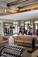 Ein Fitnessraum mit Trainingsgeräten, einem Spiegel und großen Fenstern.