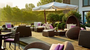 Une terrasse dotée de meubles en osier, notamment des canapés et des fauteuils, ainsi qu’une table avec des chaises.