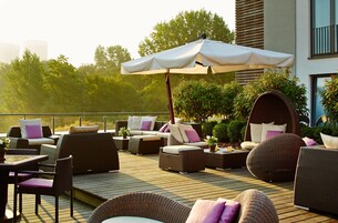 Eine Terrasse mit Korbmöbeln, darunter Sofas, Stühle und ein Tisch mit Sitzgelegenheiten.