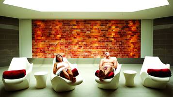 Uma área de spa com duas poltronas reclináveis e uma parede de mosaico vermelha.