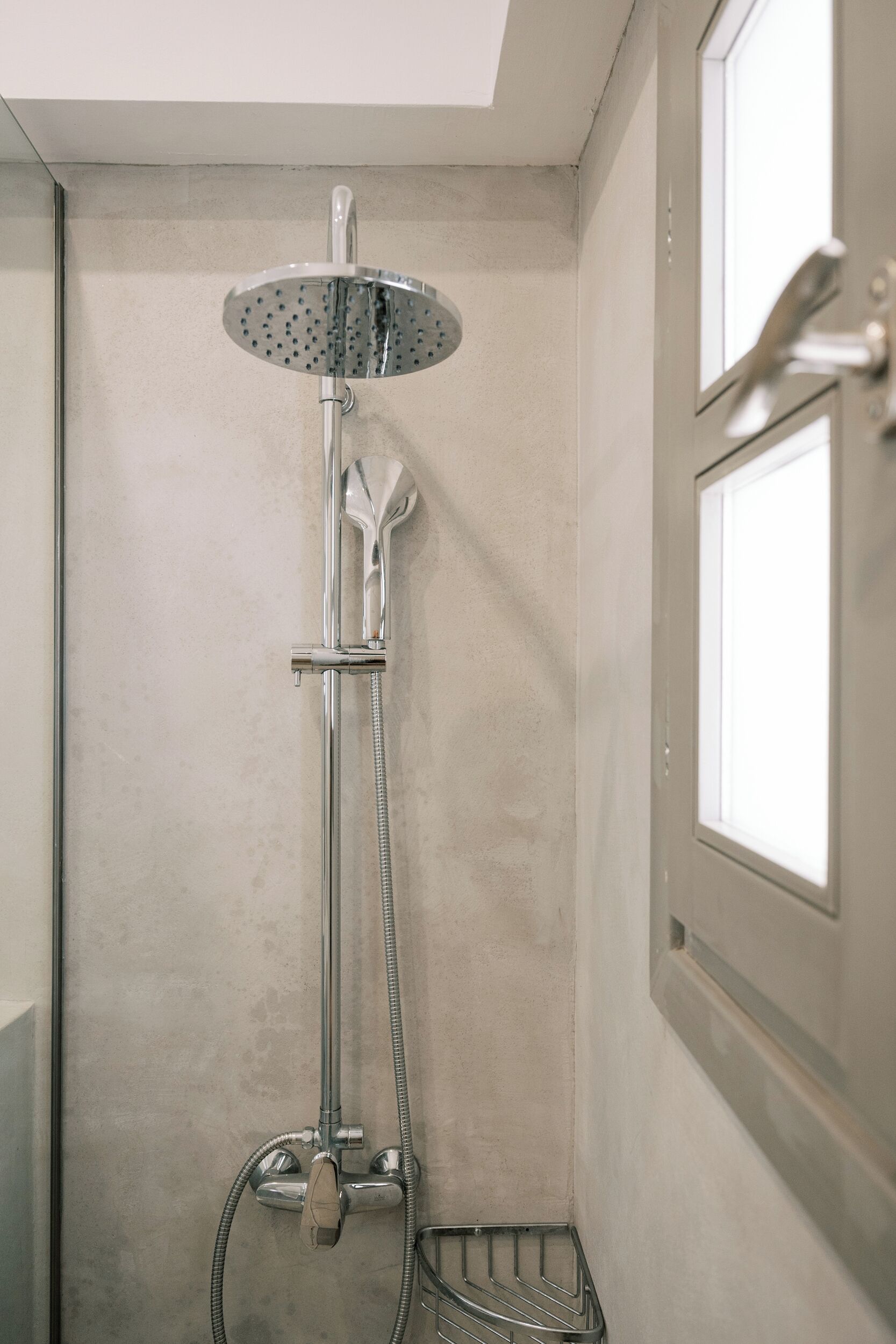 A shower with a handheld showerhead, a wall-mounted faucet, and a shower tray.