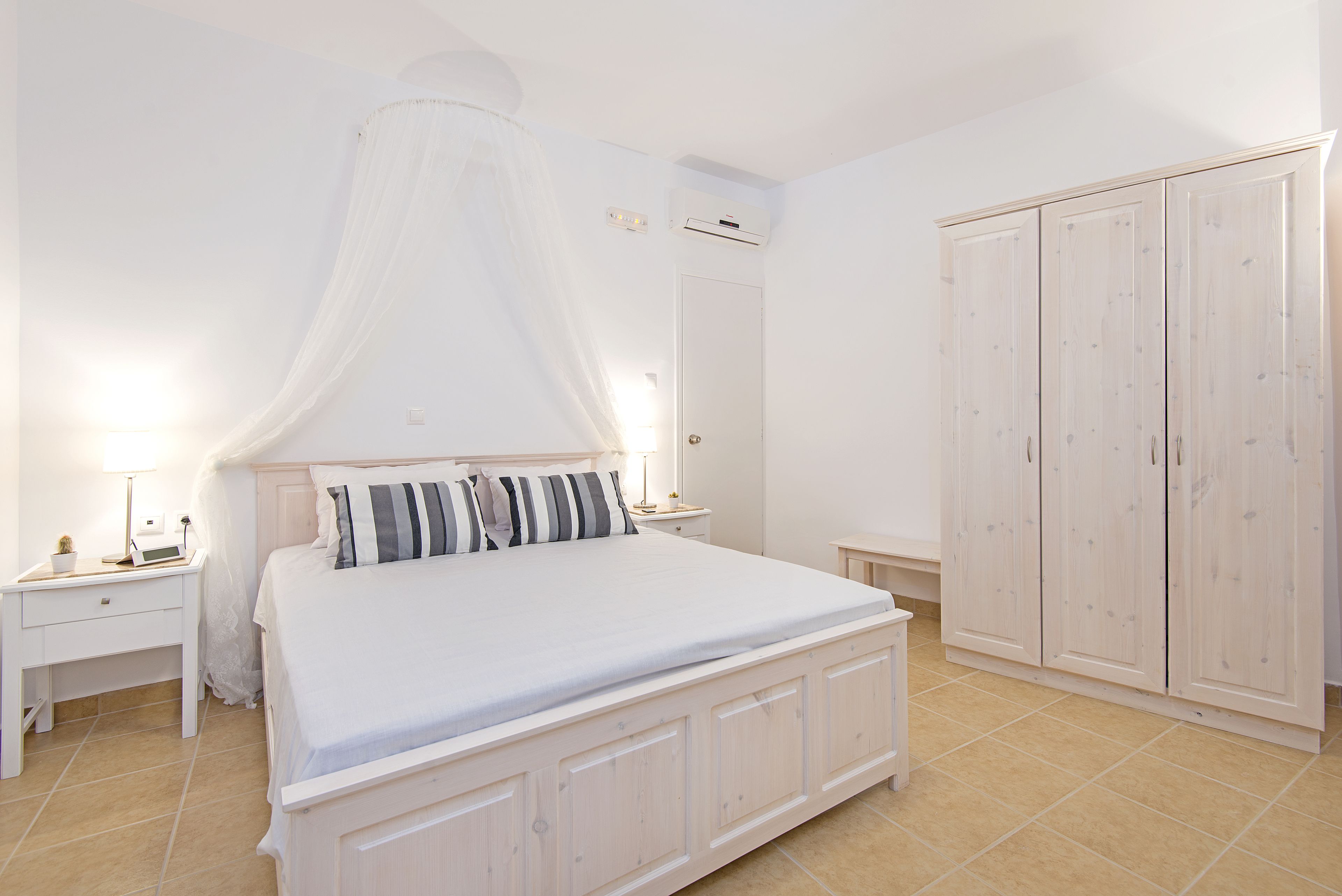 Une chambre à coucher avec un grand lit, une table de chevet, une commode, une armoire et un ventilateur de plafond.