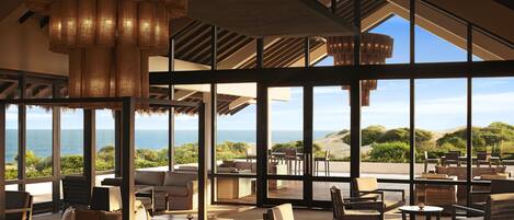 A spacious outdoor lounge area with comfortable seating and large windows offering ocean views.