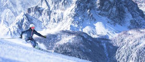 A skier on a snowy slope with a mountainous backdrop.