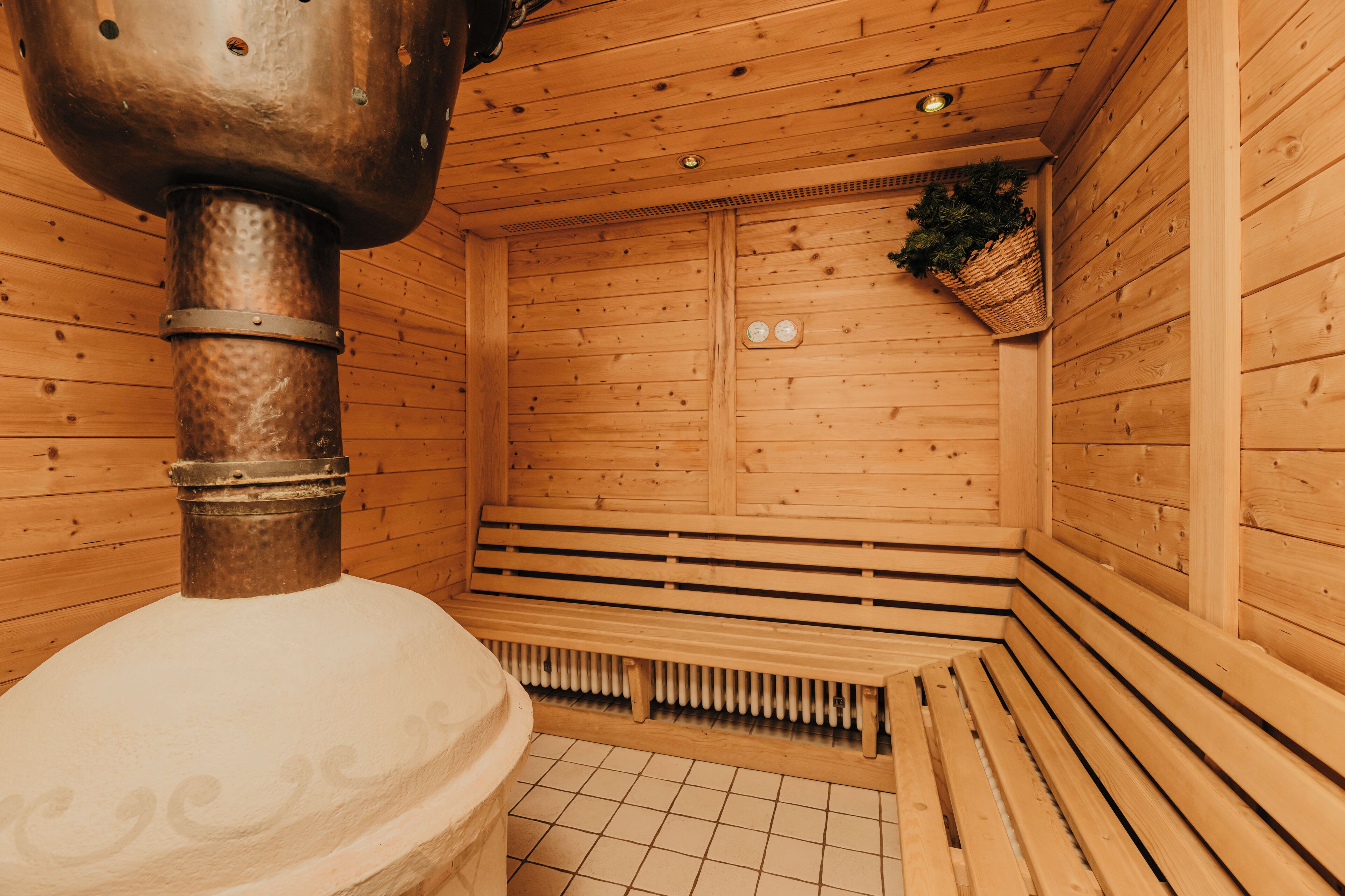 A sauna with wooden walls, a bench, and a steam vent.