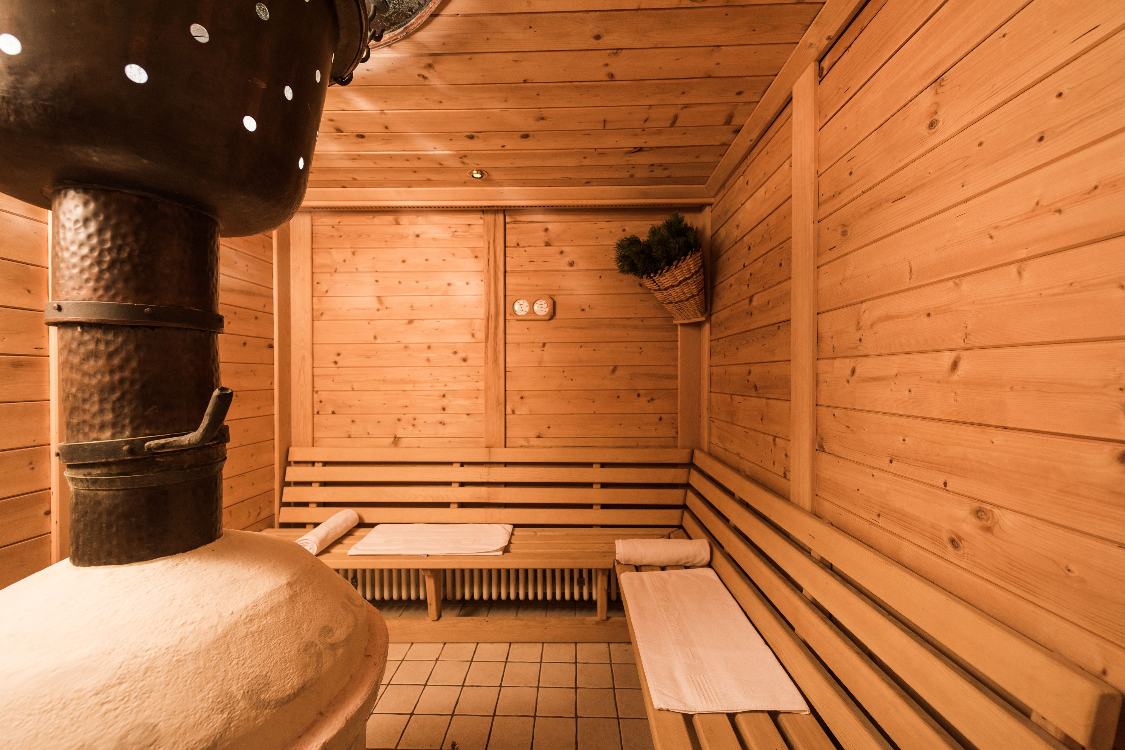 Una sauna de madera con bancos y un calentador grande.