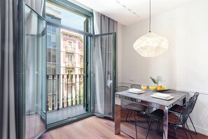 Un comedor con una mesa, sillas, una lámpara colgante y vistas al balcón exterior a través de un ventanal.