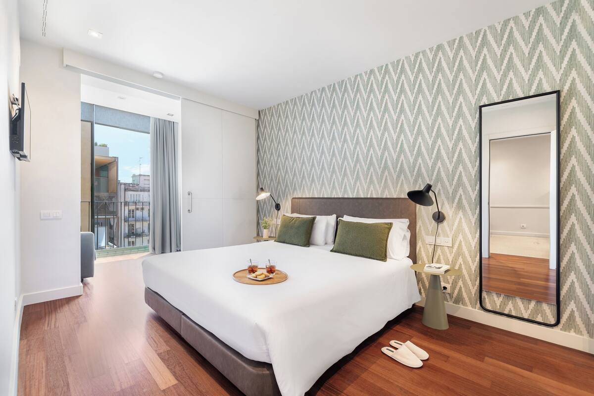Une chambre d’hôtel moderne avec un grand lit, une vue sur la ville et un balcon.