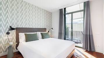 Une chambre d’hôtel avec un grand lit, une table de chevet, une table et une vue sur l’extérieur par une fenêtre.