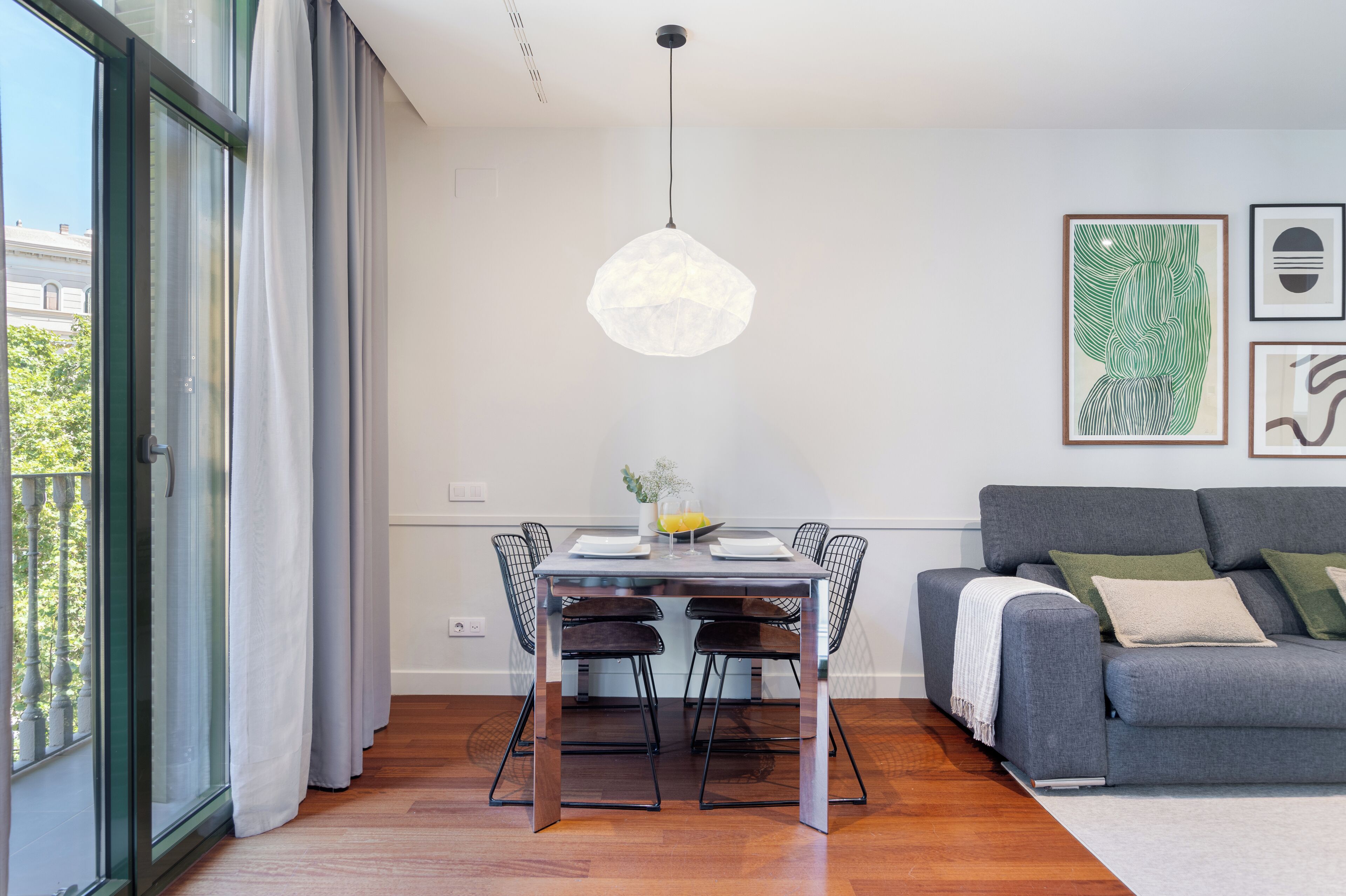 A modern dining area with a table, chairs, and a hanging light fixture.