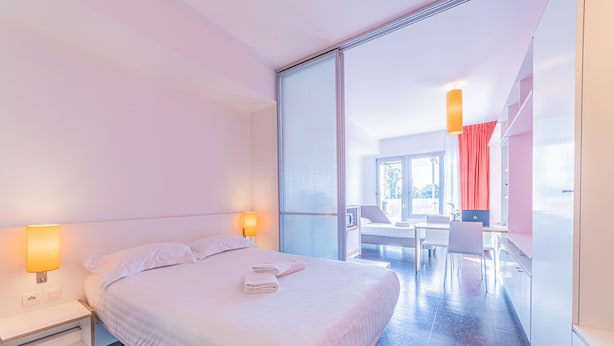 A modern hotel room with a large bed, bedside lamps, a desk, and a view of the outside. - Résidence Montempo Lyon Cité Internationale (Lyon)