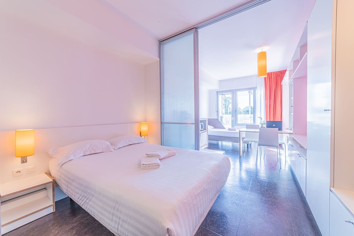Une chambre d’hôtel moderne avec un grand lit, des lampes de chevet, un bureau et une vue sur l’extérieur.