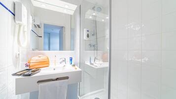 Een moderne badkamer met een witte wastafel, spiegel en een douchecabine met glazen wanden.
