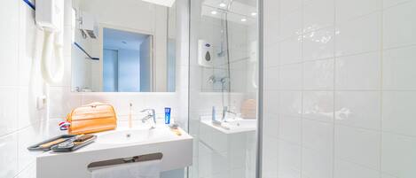 A modern bathroom with a white sink, mirror, and a glass-enclosed shower area.