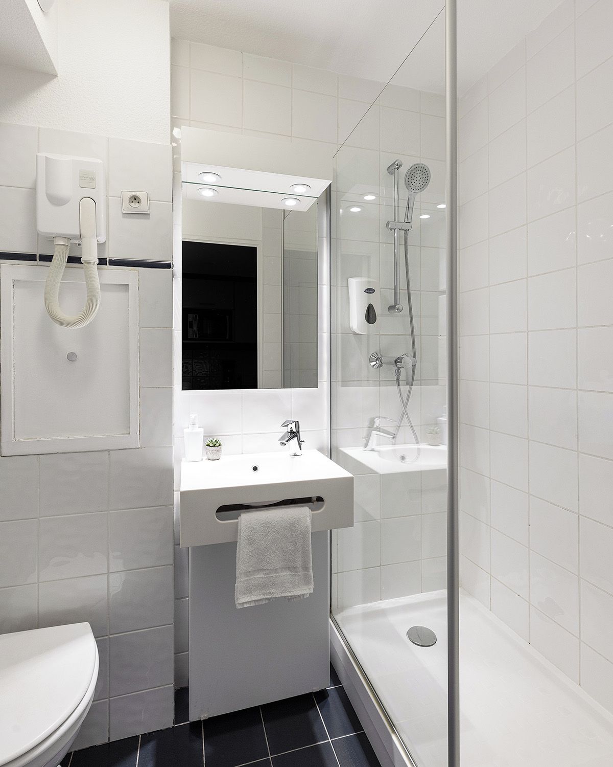 A modern bathroom with a glass shower enclosure, a white sink with a mirror above it, and a toilet.