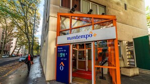 Un hotel-apartamento moderno llamado Montempo con entrada de cristal y detalles en naranja.