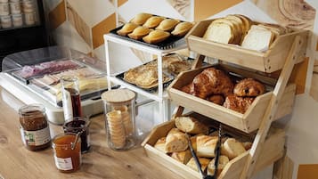 Un bufé de desayuno con diversos pasteles, pan y acompañamientos.