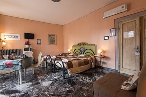 A hotel room with a bed, a desk, a chair, a radiator, a television, and a door. - Soggiorno Fortezza Fiorentina (Florence)