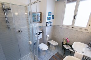 Un baño con ducha de vidrio, inodoro, bidé y lavamanos.