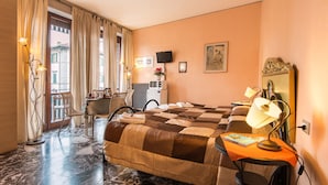 A hotel room with a bed, a desk with a lamp, a chair, a small table with a book, a TV, and a window with curtains. - Soggiorno Fortezza Fiorentina (Florence)