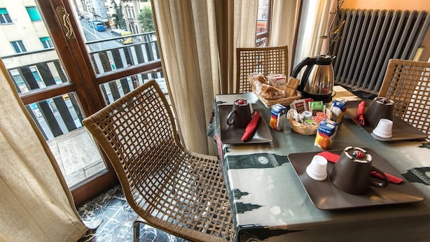 A dining area with wicker chairs, a table set with a teapot, cups, and a basket of bread. - Soggiorno Fortezza Fiorentina (Florence)