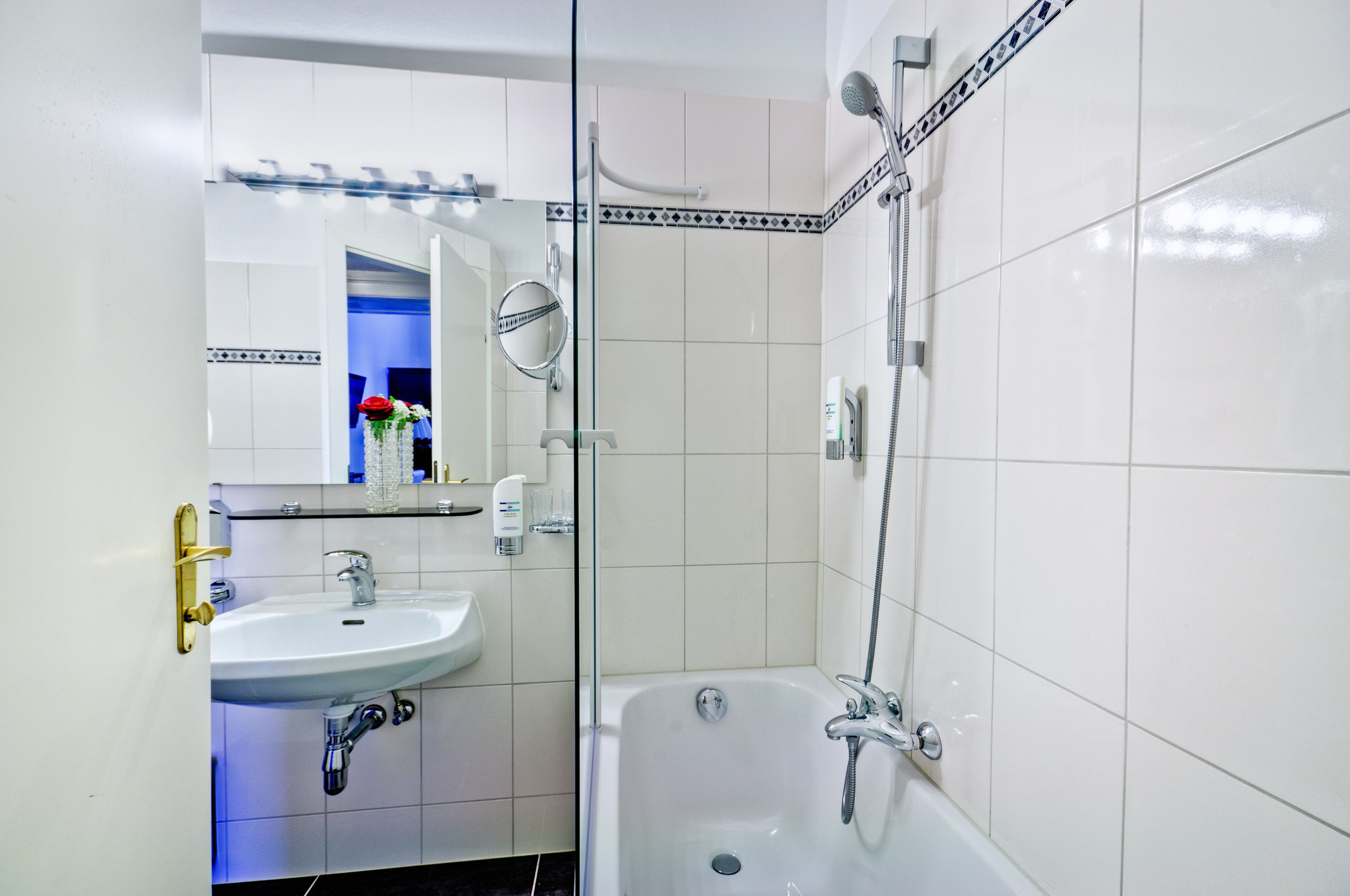 A bathroom with a sink, mirror, and bathtub.