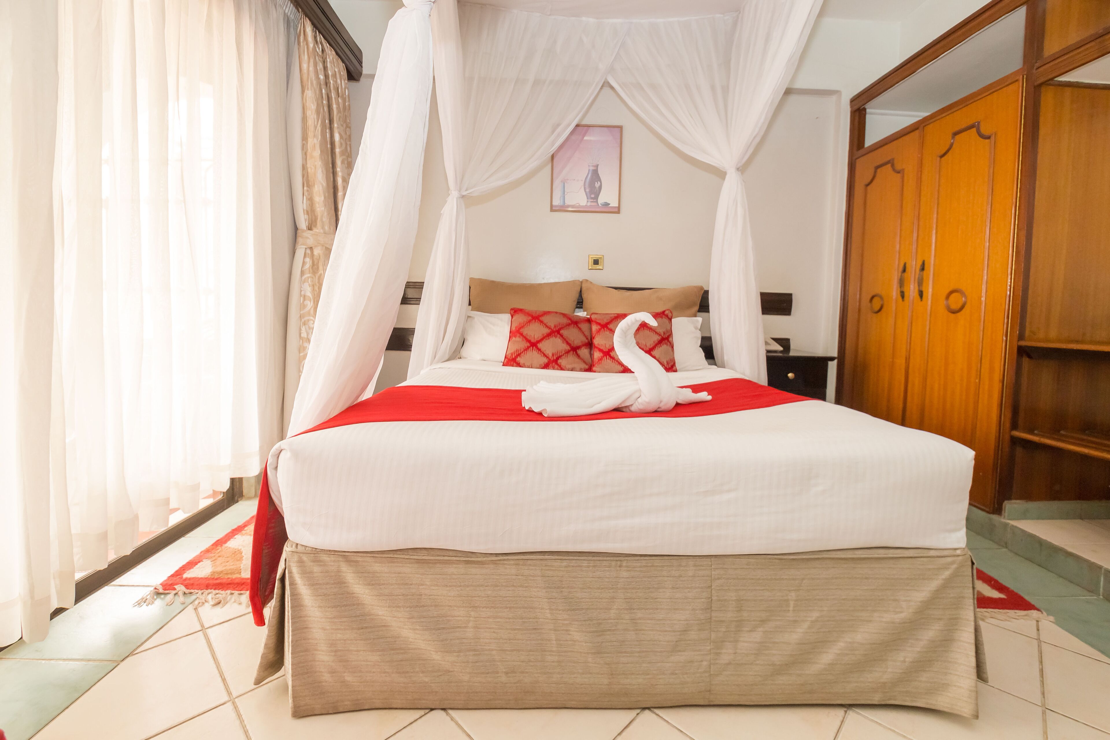 Ein Hotelzimmer mit Bett, Kleiderschrank und Vorhang.